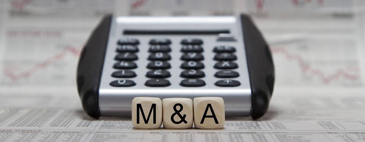 wooden blocks with "M&A" in front of a calculator