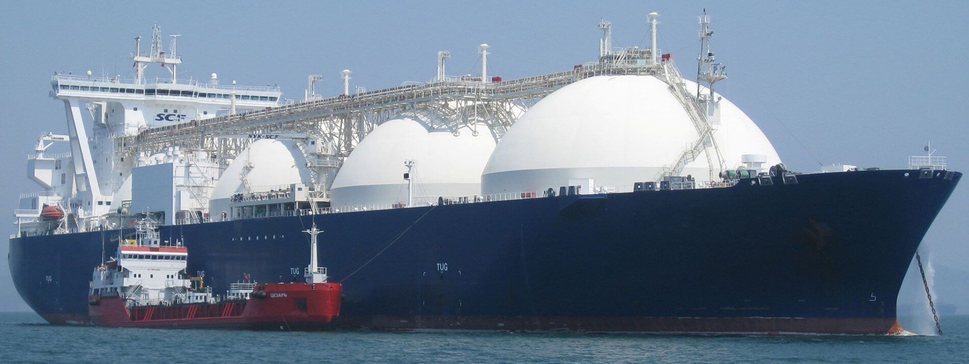 Another large Liquid Natural Gas (LNG) Carrier with adjacent red tug and a ship loan